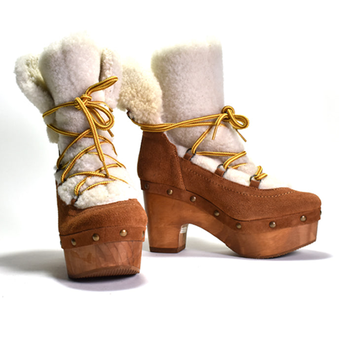 Brown platform boots with white fur lining and yellow laces on a white background