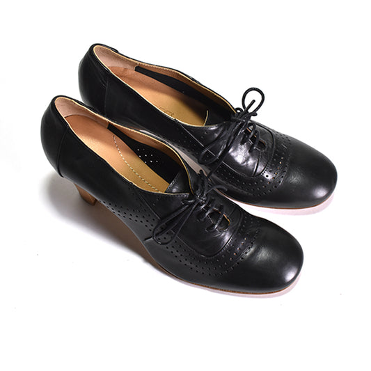 Pair of black pointy laced shoe with tan heels