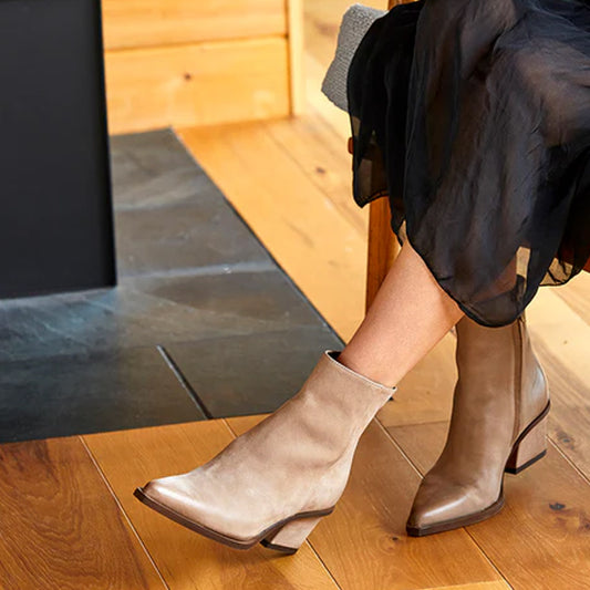 beige Western-style ankle bootie with a wrapped heel, visible zipper, and nubuck upper material.