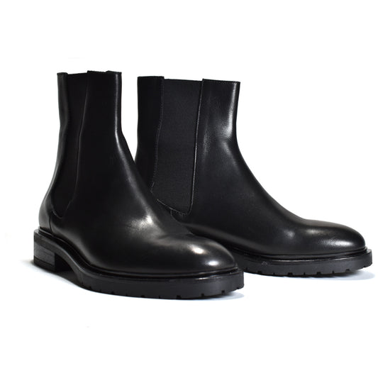 A pair of black leather Chelsea boots with elastic side panels and chunky lug soles, photographed on a clean white background.