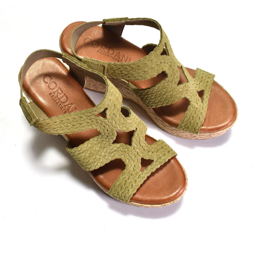 Green wedge sandals with woven sole on a white background