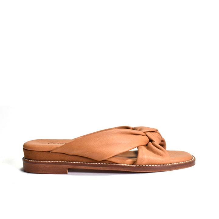 Tan sandal with criss-cross strap design on a white background