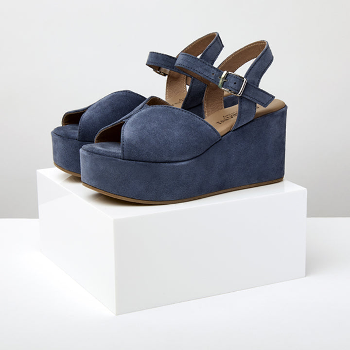 A pair of blue suede platform sandal with an adjustable ankle strap and a wedge heel.