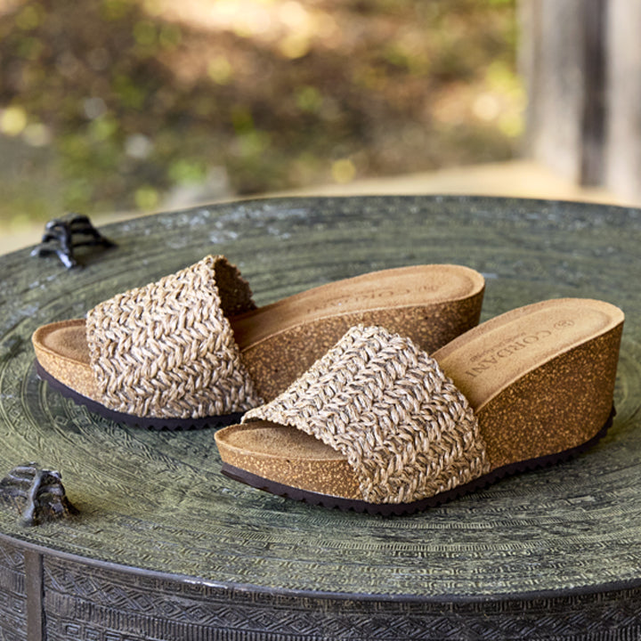 Pair of cork sandals on a textured surface with a blurred natural background