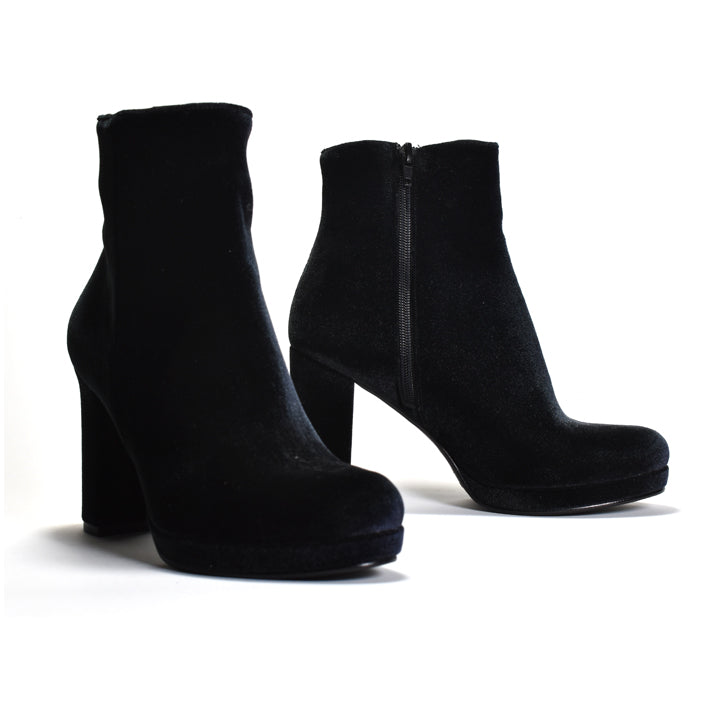 A pair of black velvet ankle boots with high block heels and platform soles, shown on a clean white background.