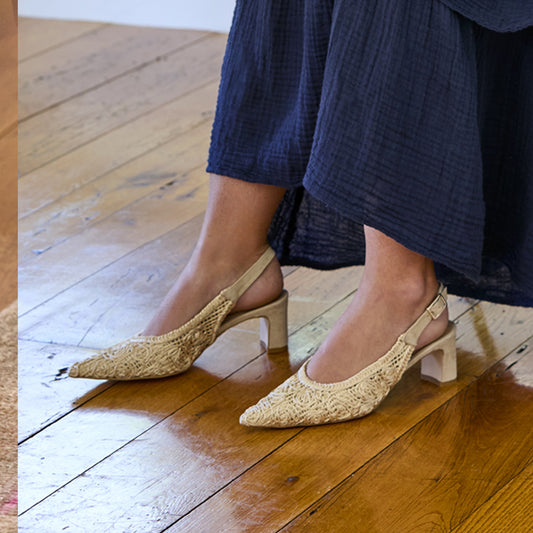 Beige lace shoes worn with navy dress on a wooden floor