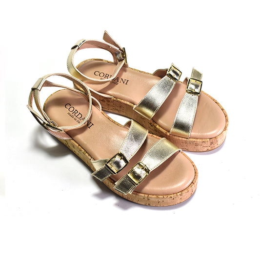 A gold two-strap sandal with adjustable metal buckles, a cork-wrapped platform, and a leather ankle strap.