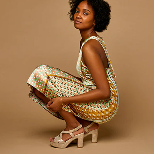 woman wearing metallic platform sandals with criss-crossing straps, an adjustable metal buckle, and a chunky heel.