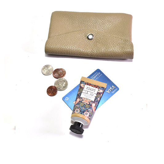 Beige wallet with coins, Visa card, and hand cream on a white background