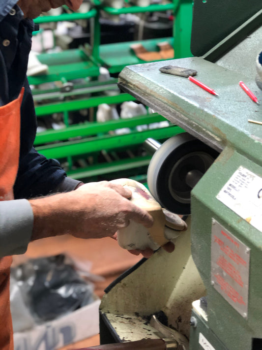 Artisan sanding the sole of a shoe.
