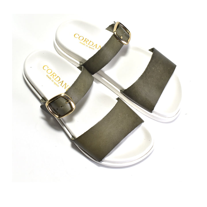 Pair of sandals with green straps and white soles on a white background