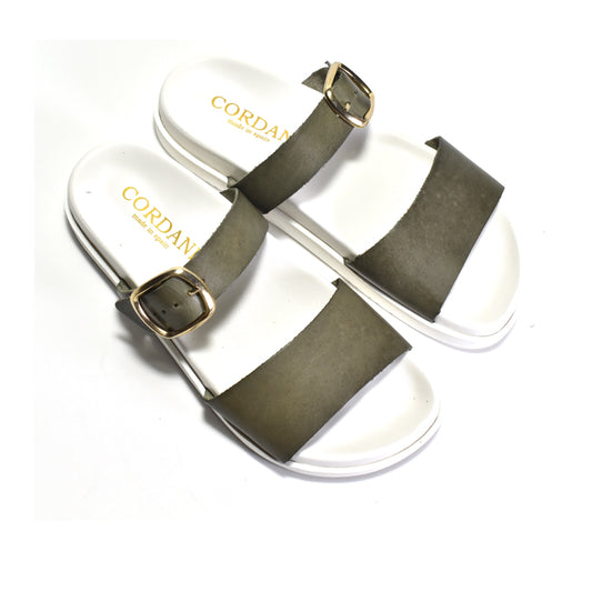 Pair of sandals with green straps and white soles on a white background