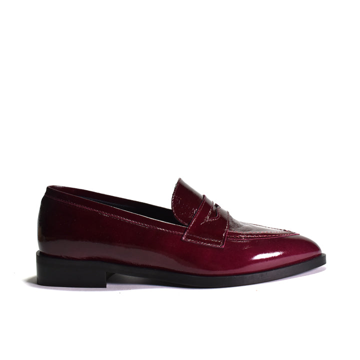 A single glossy patent leather penny loafer in deep burgundy, shown from a side profile against a plain white background.