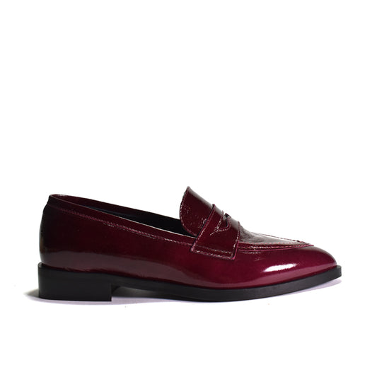 A single glossy patent leather penny loafer in deep burgundy, shown from a side profile against a plain white background.