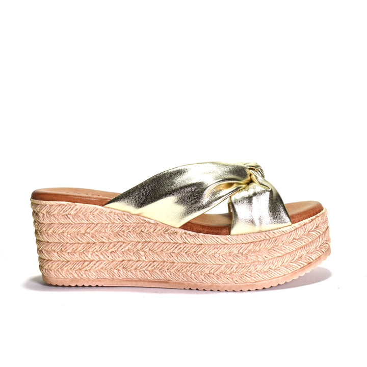 Gold espadrille sandal with a pink woven sole on a white background