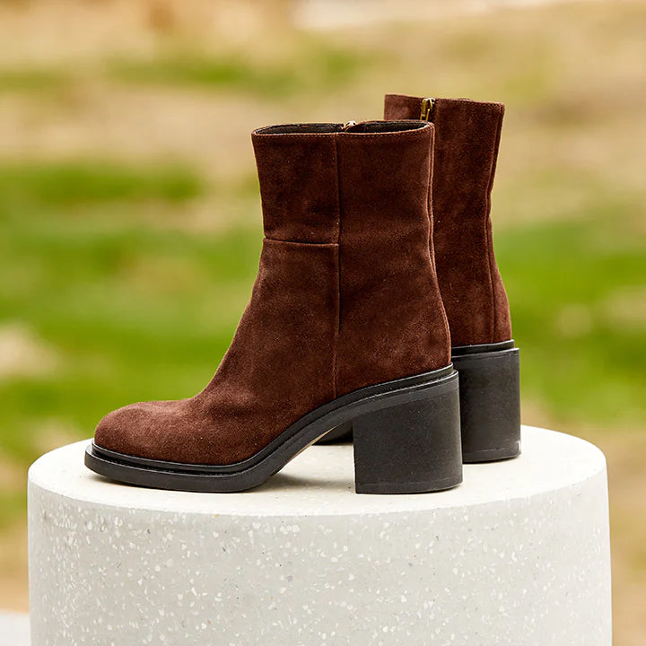A pair of brown suede ankle boot with a rubber heel and inside zipper