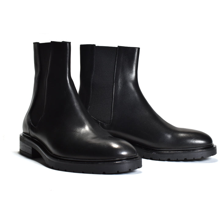 A pair of black leather Chelsea boots with elastic side panels and chunky lug soles, photographed on a clean white background.