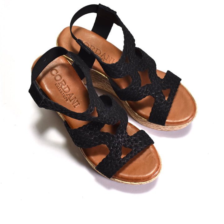 Black wedge sandals with woven sole on a white background