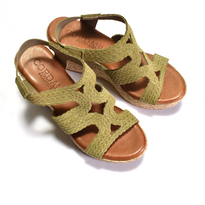 Green wedge sandals with woven sole on a white background