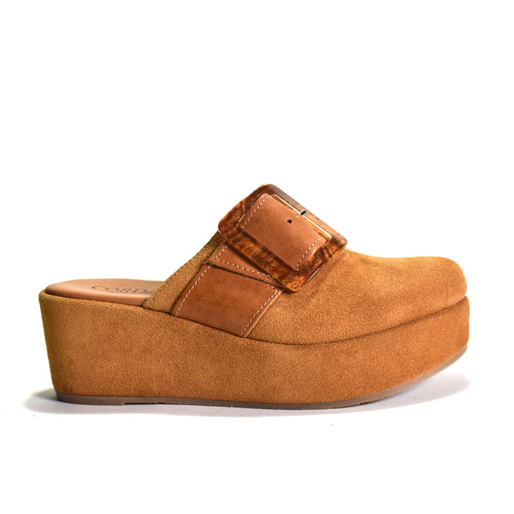 A single tan platform mule sandal with a suede-like finish, featuring a wide strap with a decorative buckle detail, shown from a side profile on a white background.