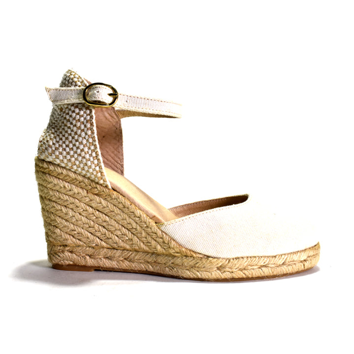 White wedge sandal with a woven sole on a white background
