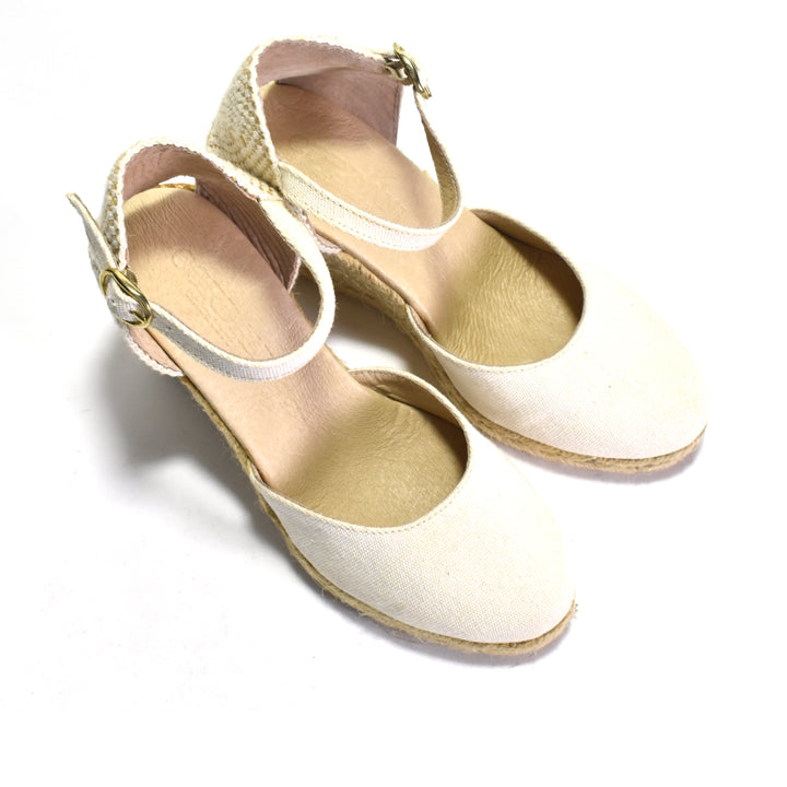 Pair of white sandals with straw accents on a white background