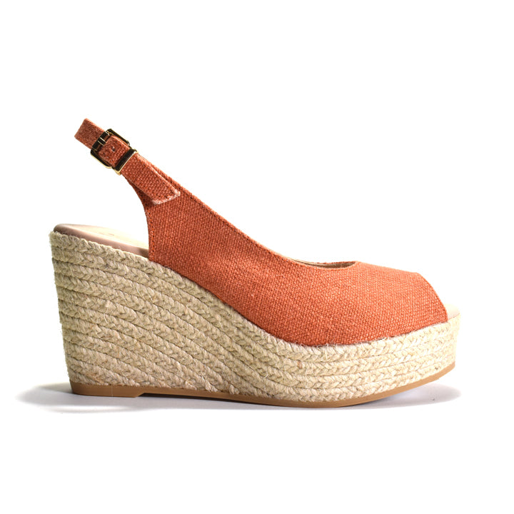 Terracotta colored wedge sandal with woven sole on a white background