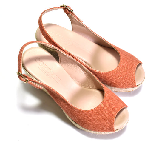 Pair of orange open-toe slingback heels on a white background