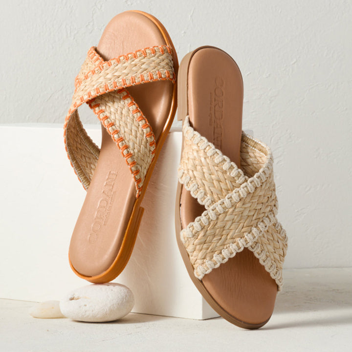 Pair of woven sandals with orange accents on a white background