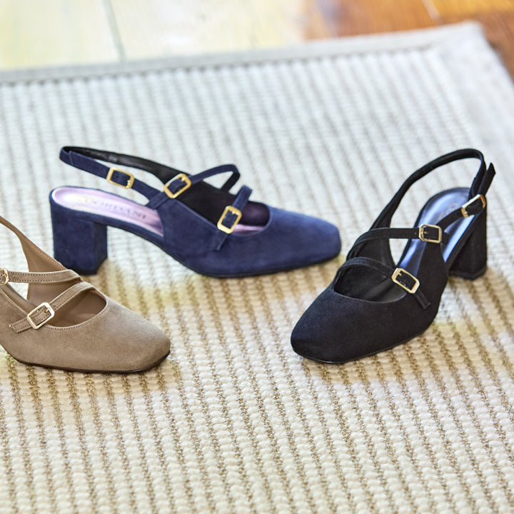 Three pairs of women's shoes in navy, black, and beige on a textured surface.