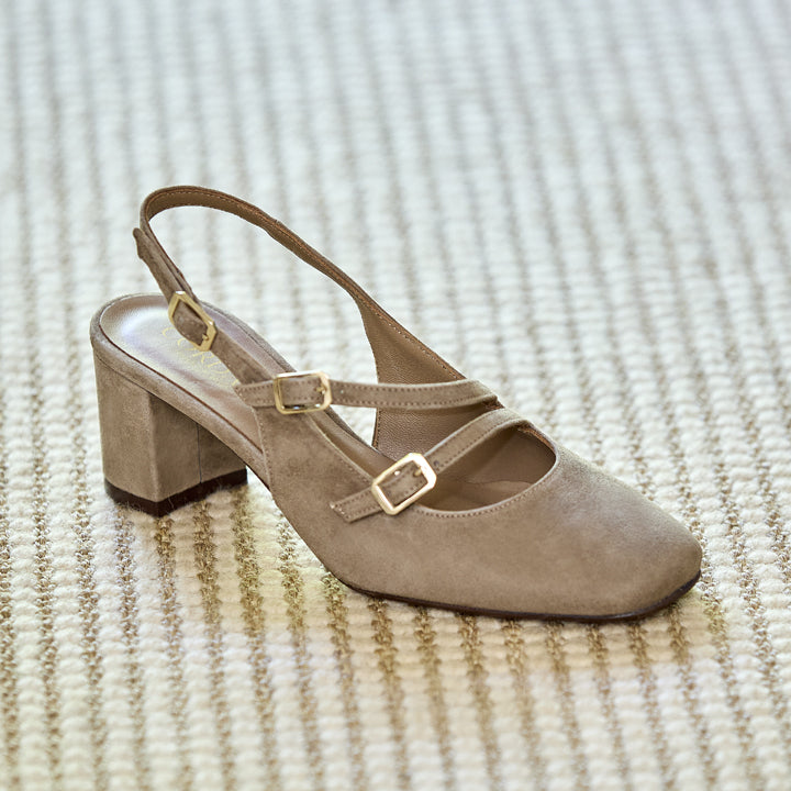 Beige sandal with a block heel on a textured beige surface