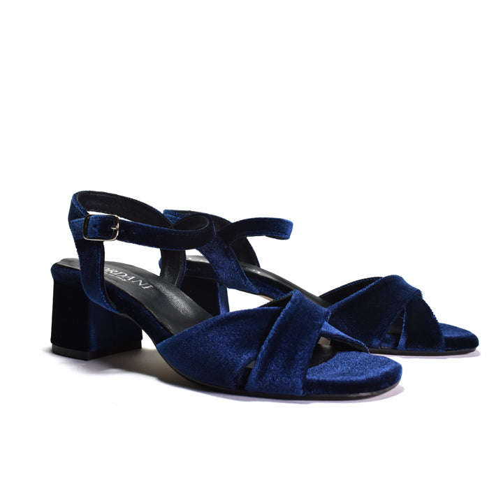 A pair of navy blue velvet block-heel sandals with crisscrossing front straps and adjustable ankle straps, shown on a plain white background.