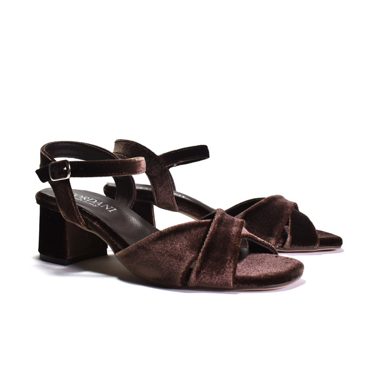 A pair of dark brown velvet block-heel sandals with crisscross front straps and ankle straps, shown on a clean white background.