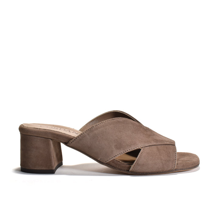 A taupe brown suede mule sandal with a block heel and crisscrossing front straps, shown from a side profile on a white background.