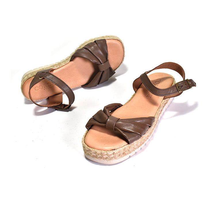 dark brown nappa leather sandal with a woven rafia wrapped wedge, leather lining, and an adjustable buckle strap on a white background.