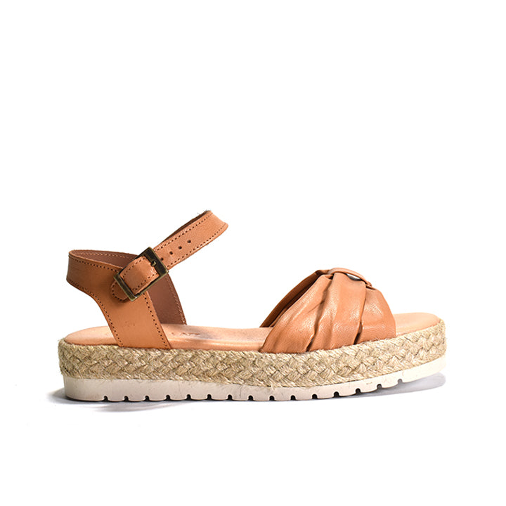 A brown nappa leather sandal with a woven rafia wrapped wedge, leather lining, and an adjustable buckle strap on a white background.