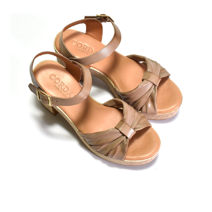 Pair of tan sandals with criss-cross straps on a white background