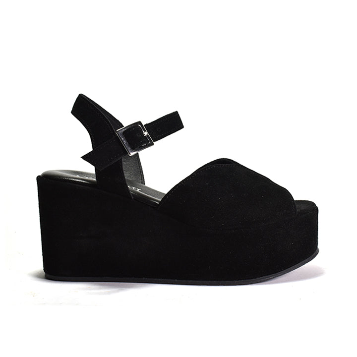 A black suede platform sandal with an adjustable ankle strap and a wedge heel.