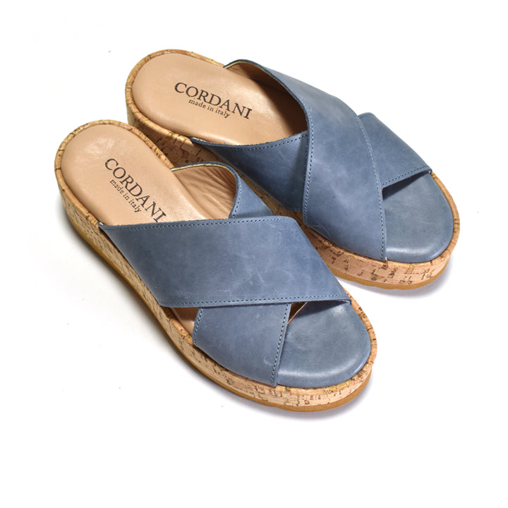 A pair of blue leather slide sandals with cork wedge soles, shown on a clean white background. The brand name CORDANI is clearly visible on the insoles.