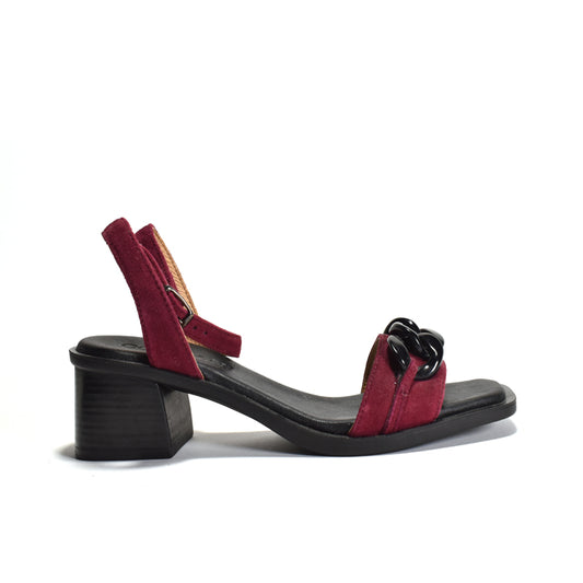 A maroon sandal with a decorative chain on a stacked black leather heel, with adjustable ankle wrap and metal buckle.