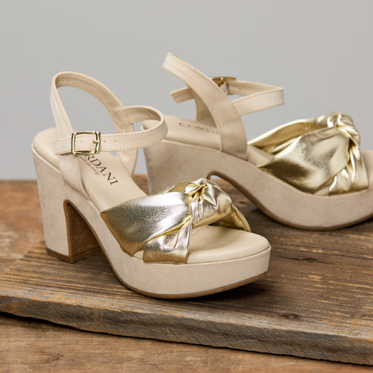 Beige high-heeled sandals with gold accents on a wooden surface