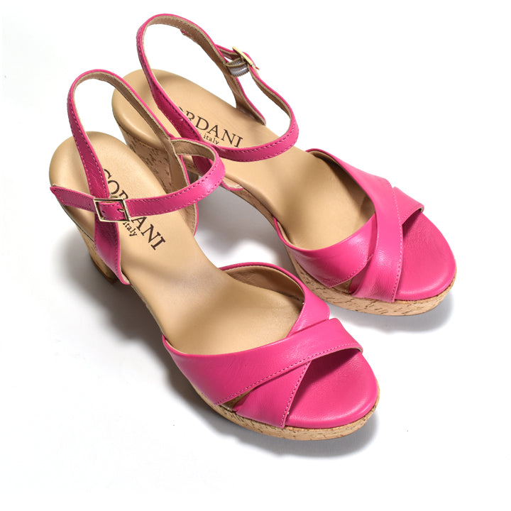 A pair of bright pink leather wedge sandals with crisscross straps, ankle straps, and cork-wrapped esoles, shown on a white background. The brand name 'CORDANI' is visible on the insoles.