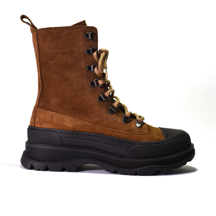 A brown suede lace-up boot with a chunky black sole and metal eyelets, shown from a side profile on a white background.