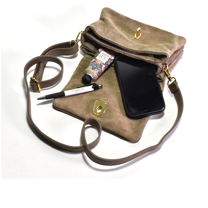 Brown suede handbag with a phone, pen, and bottle on a white background