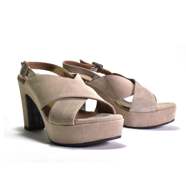 A pair of women's platform high-heel sandals in a light taupe suede-like material, featuring criss-cross ankle straps and a block heel, shown on a white background.