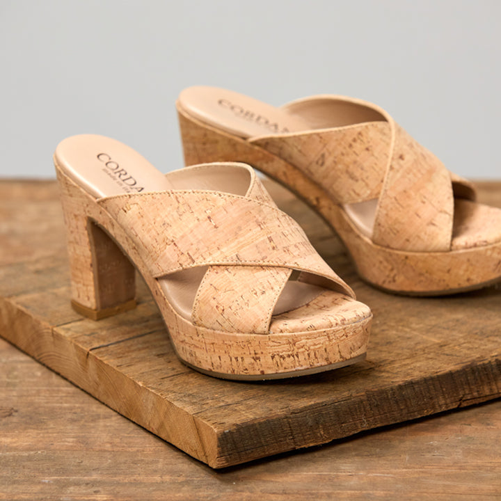 Pair of cork sandals on a wooden surface with a neutral background