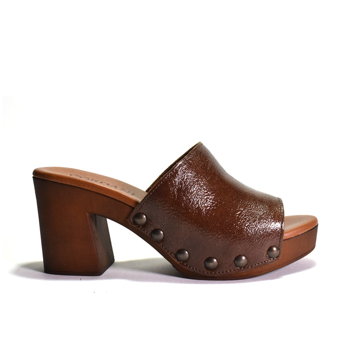 A brown leather clog sandal with a chunky block heel, platform sole, and dark metal studs, shown from a side profile on a white background.