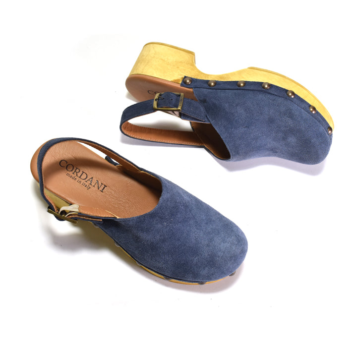 A pair of blue suede clogs with LIGHT wood-look soles and gold-tone hardware, shown on a white background. One clog is upright and the other is angled on its side, displaying the tan insole with the brand name 'CORDANI'.