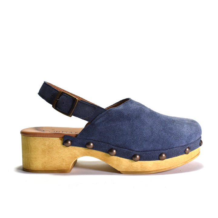 A single blue suede clog shoe with a chunky light wood platform heel and bronze metal studs, shown from a side profile on a white background.