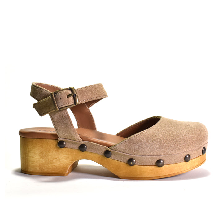 A single women's clog sandal in taupe suede with a chunky wooden platform heel, an ankle strap with a buckle, and dark metal studs, shown from a side profile on a white background.